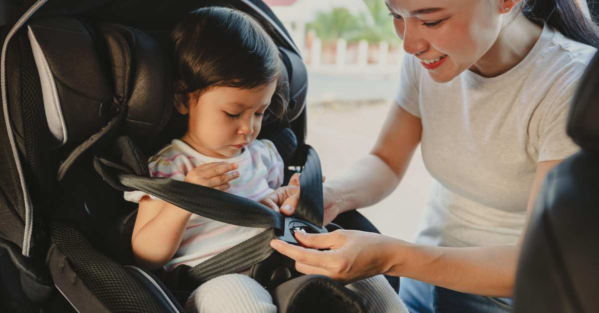 Peuter wordt door moeder in de auto gezet.